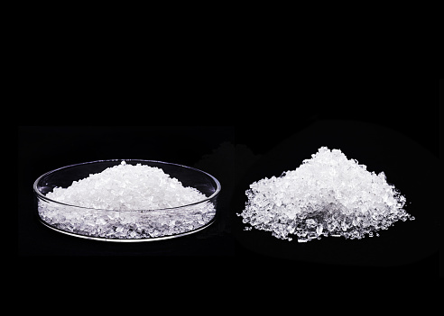 sodium chloride in petri dish, known as salt or table salt, important food preservative and popular seasoning, isolated on black background