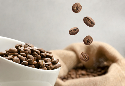 Coffee concepts. Coffee beans in a coffee cup and group of coffee beans pouring in a burlap sack