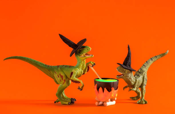 Two funny dinosaurs wearing witch hats are brewing potion in pot on  orange background. Halloween greeting card.