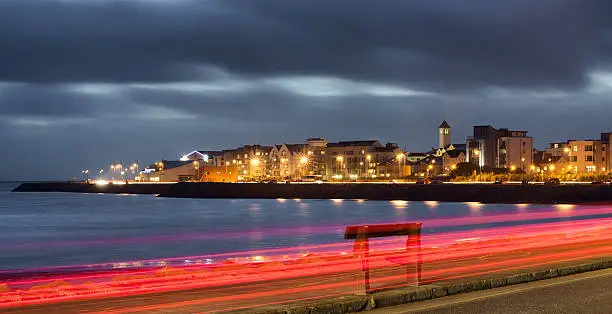 City on the bank of ocean bay and light trails at night. Salthill, Galway
