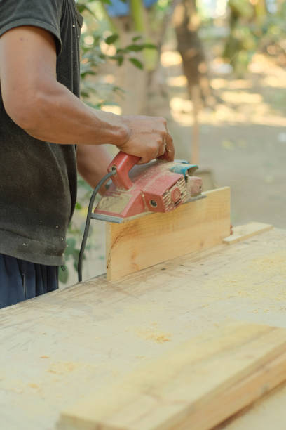 A carpenter works in a workshop. Joiner's grinders, furniture manufacturing. A carpenter is grinding a wooden part with an electric sander. place to insert text