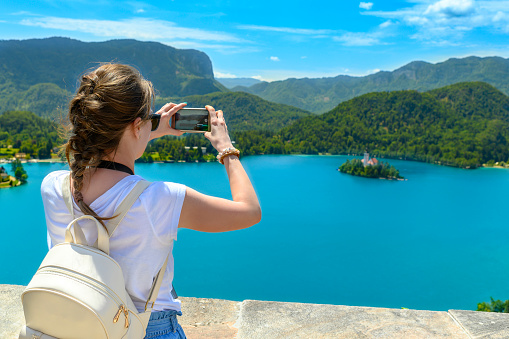 Tourist taking photos and enjoying view of lake Bled, Slovenia