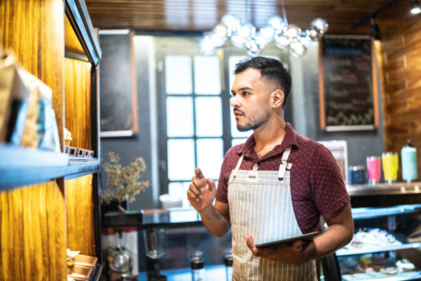 Small business owner young man working using digital tablet at a coffee shop