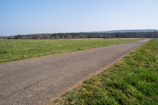 Paved walkway in the landscape on a sunny spring day with blue sky