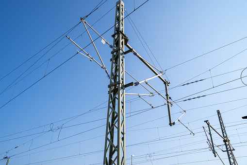 Metal pole with electric wires for rail transportation in the blue sunny sky