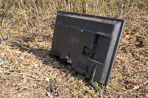Old broken television discarded by people in nature