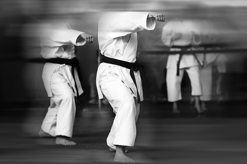 Abstract black and white karate background. The concept of expressionism and motion blur with a barely visible silhouette of an athlete in a white kimano.