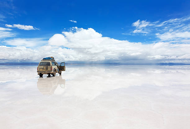 Jeep on the reflected surface of Salar de Uyuni lake in Bolivia