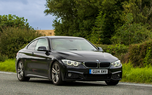 Woburn, Beds, UK - Aug 19th 2023:  2014 black diesel engine BMW 420 car travelling on an English country road.