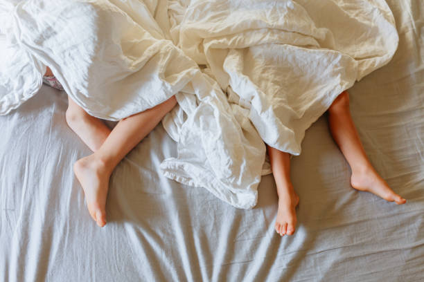 istock feets of two children sleeping under white bedsheet 1625618212
