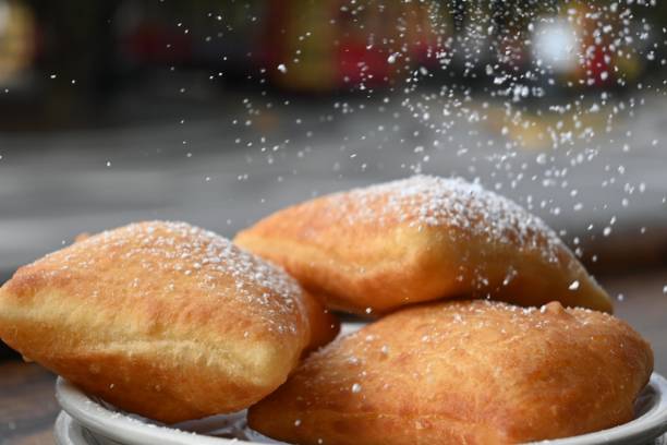 Pouring power sugar on traditional Beignets. Pouring power sugar on traditional Beignets with copy space beignet stock pictures, royalty-free photos & images