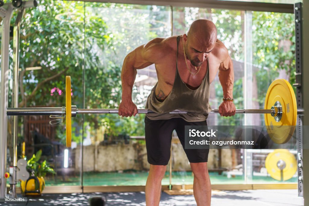 Young athlete man exercising with barbell in the gym Body Building Stock Photo