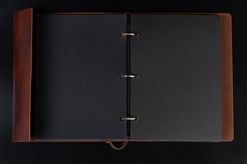 Open binder  with black pages in brown leather cover
