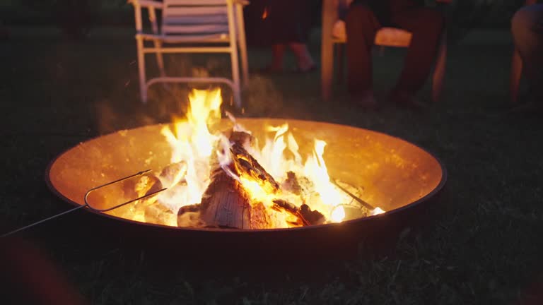 Friends sitting around a campfire together on a summer evening