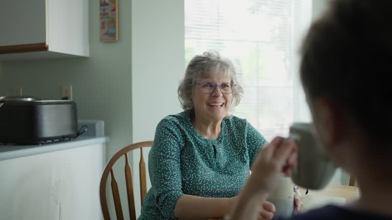 Smiling mature woman chatting with her daughter over tea during a visit