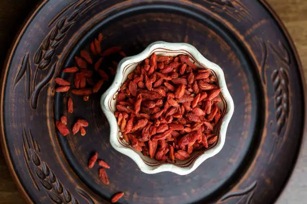 Dried goji berries in a clay bowl.