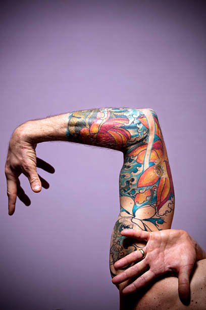 tattoo portrait mid adult man arm aloft with fingers on hands spread and wedding band on ring finger.  vertical composition. forearm tattoos men stock pictures, royalty-free photos & images