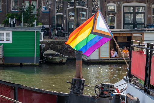 Amsterdam, Netherlands - 6 September 2022: Gay rainbow flag on a barge boat at the waterfront
