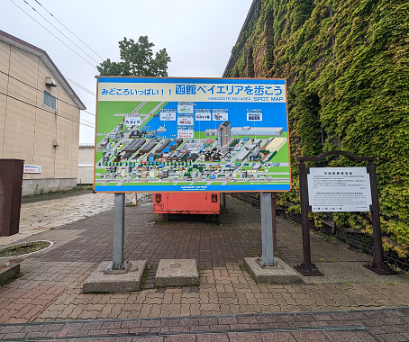 Hakodate, Japan - June 10, 2023; An illustrated, mulilingual map clearly shows the buildings of the Hakodate Bay Area, an industrial, retail and hotel district. Spring morning in the rain in Oshima Subprefecture, Hokkaido.