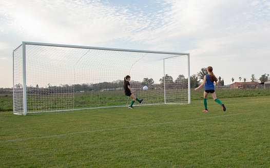Teenage girls playing soccer on grass pitch