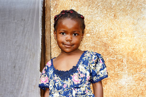 Sweet little African girl Portrait of a cute and sweet little black African girl, smiling but looking a bit shy, posing in front of her house. More people at: http://tonytremblay.com/sylvie/people.jpg cameroon stock pictures, royalty-free photos & images