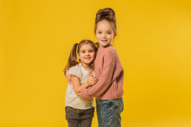 istock Two blonde girls in studio on yellow background 1625841322