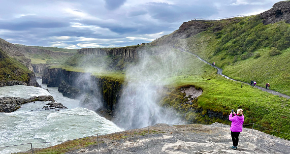 Middle aged woman at Gulifoss waterfall located in the canyon of the Hvítá river in southwest Iceland.