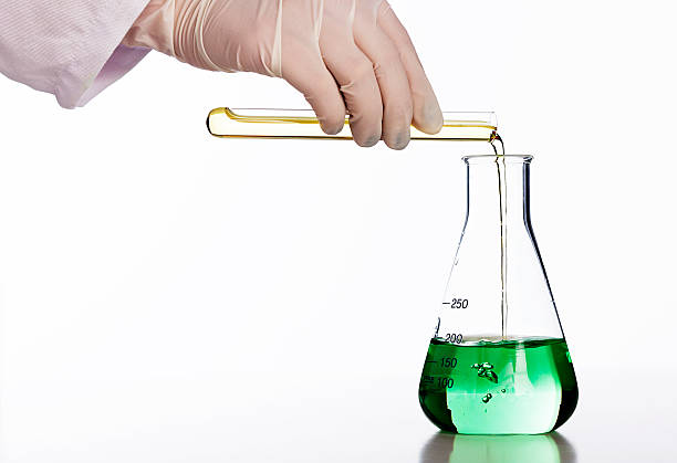 istock Scientist's gloved hand  pours chemical into flask of green liquid 162586521