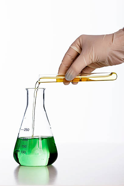 istock Gloved hand pours chemical into lab flask against white background 162586658