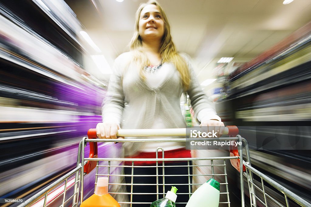 Rubia carreras de compras por el supermercado con desenfoque multicolored - Foto de stock de Carrito de la compra libre de derechos
