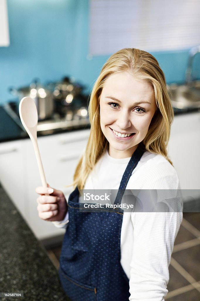 Mulher jovem feliz cozinhar elevadores colher de pau e sorrisos orgulhosamente - Royalty-free 20-29 Anos Foto de stock