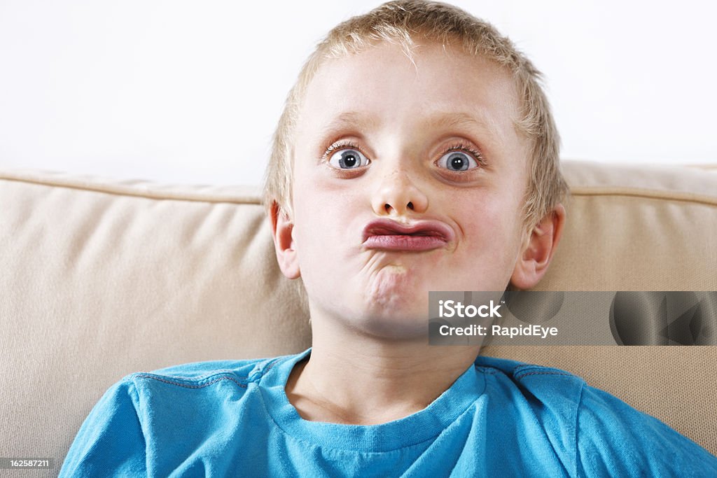 Cute 8 year old blond boy pulls a funny face This cute blond 8 year old boy grimaces mischievously, pulling a funny face.  8-9 Years Stock Photo