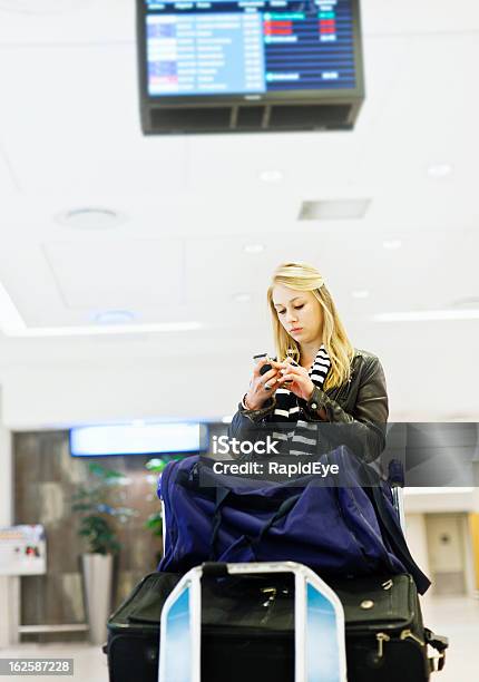Foto de Grave Jovem Viajante No Aeroporto Com Bagagem Envia Uma Mensagem De Texto e mais fotos de stock de Aeroporto