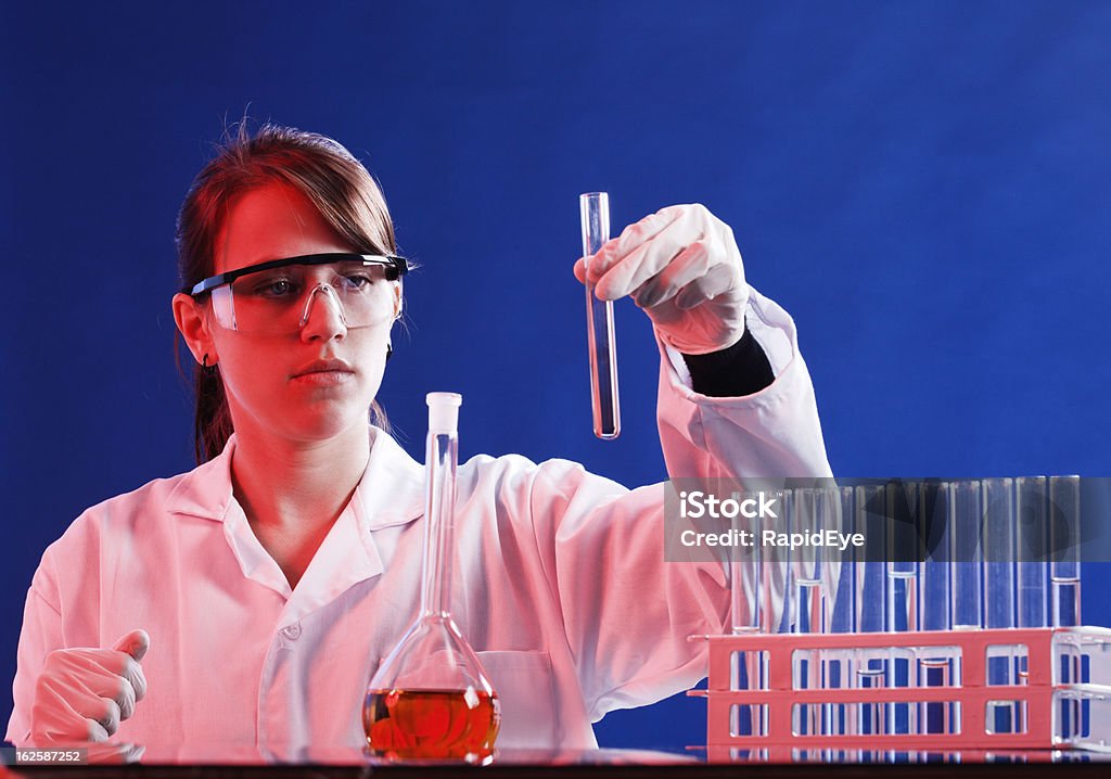 Jeune femme scientifique chèques de produits chimiques dans le tube à essai, de se concentrer à fond - Photo de Adulte libre de droits