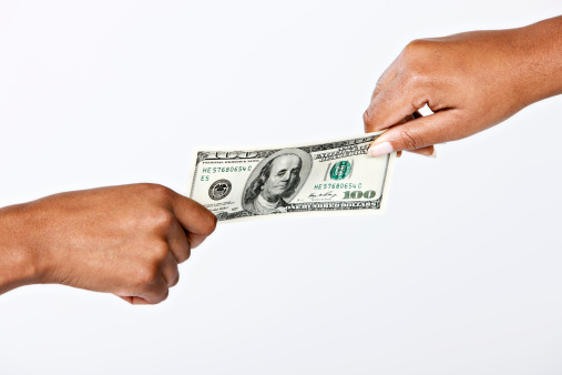 Two female hands have a tug-of-war with a $100 bill, against a white background. 