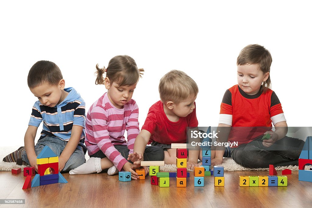 Four children are playing on the floor Four children are playing on the floor with blocks Alphabet Stock Photo