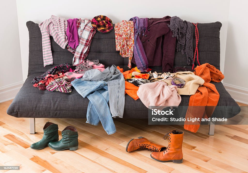 Clothes and boots placed haphazard over floor and sofa What to wear? Messy colorful clothing on a sofa. Clothing Stock Photo