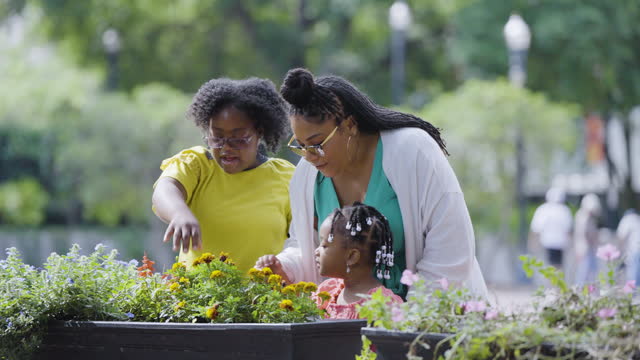 Girl with down syndrome, family admire flowers in planter