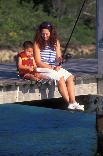 Mother with son sitting on a pier fishing, Florida Keys, USA