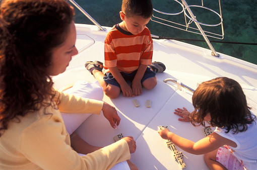 Mother with children playing dominoes on boat deck, Florida Keys, USA