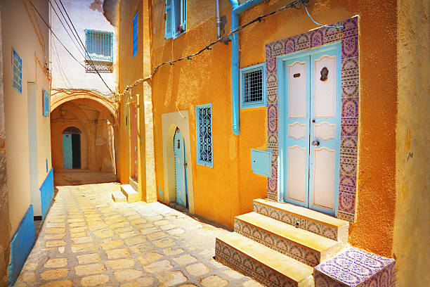 arabian cobblestone street with orange colored building - tunisia stok fotoğraflar ve resimler