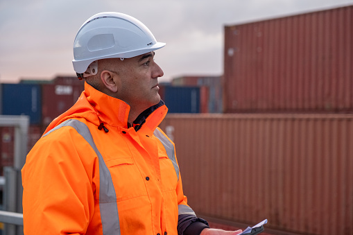 A male port worker looking at the stacked containers