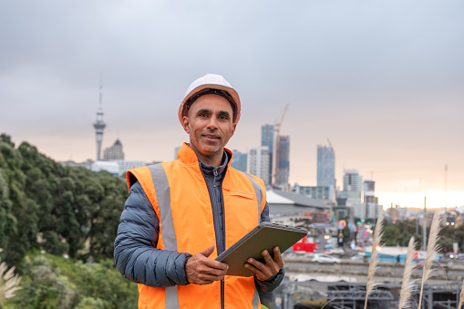 A male engineer with a digital tablet standing with Auckland city scape in the background