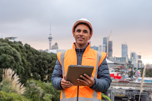 A male in construction clothing holding a digital tablet