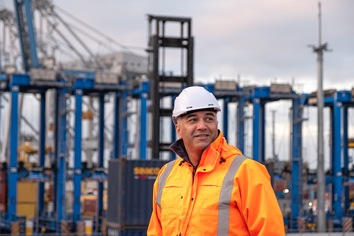 Portrait of male port worker against cranes
