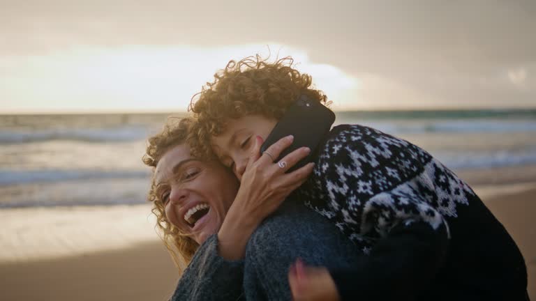 Cute kid talking phone on coast vacation with mother closeup. Happy family speak