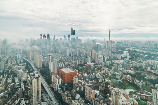 A high-altitude panoramic cityscape showing the buildings and junctions of Yuexiu and Tianhe Districts in Guangzhou. The picture includes Guangzhou Inner circle Expressway, Dongshankou Residential Area, the Pearl River, Zhujiang New Town, Canton Tower and other landmarks. Some mist floats between the skyscrapers.