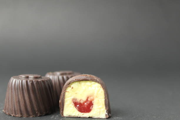 istock Chocolate case candy filled with mango, passion fruit, cherry, raspberry with yellow and red filling on a black background with space for text and copyspace. Delicious sweets, sweets, diet-free day, chocolate, desserts for tea, coffee 1626140172
