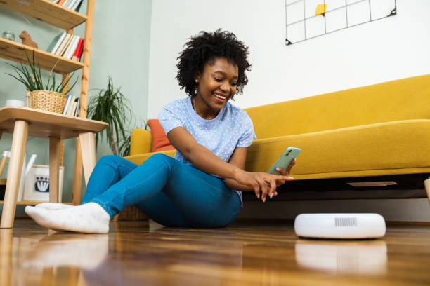 istock Young woman turning on her robot vacuum cleaner using a smart app 1626174518