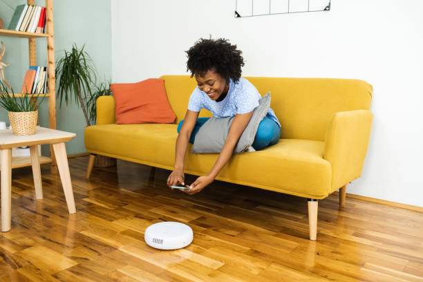istock Happy woman using her smartphone and turning on robotic vacuum cleaner 1626174523